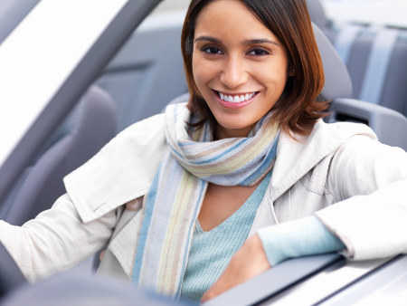 Closeup face portrait of a young smiling woman sitting in her car